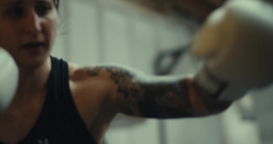 Woman with white gloves throwing boxing punches at a punching bag