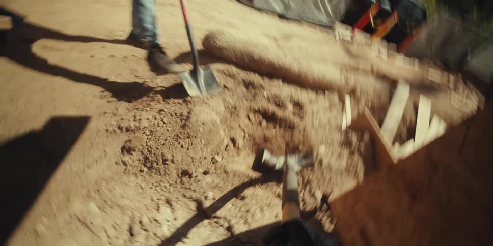 A construction worker shovels dirt into the wheelbarrow