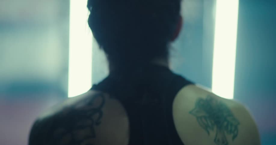 An athletic woman is exercising with her back to the camera