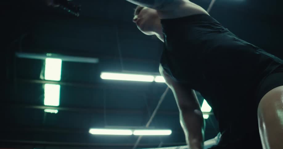 Determined woman doing cardio indoors by hitting ropes