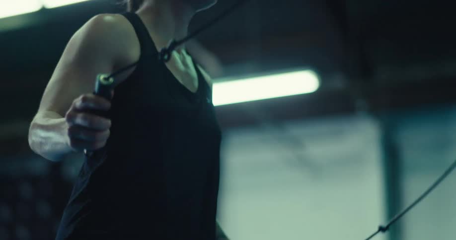 A woman is exercising while jump roping in an indoor gym