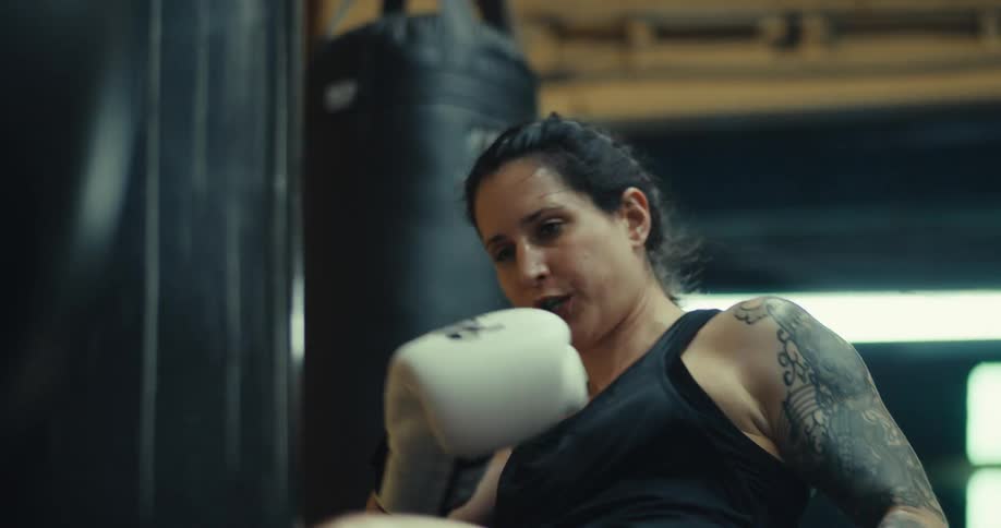Woman wearing boxing gloves and throwing punches at a punching bag
