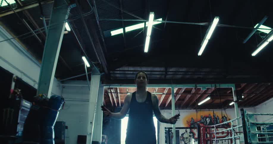 A woman is jumping rope barefoot inside of a gym