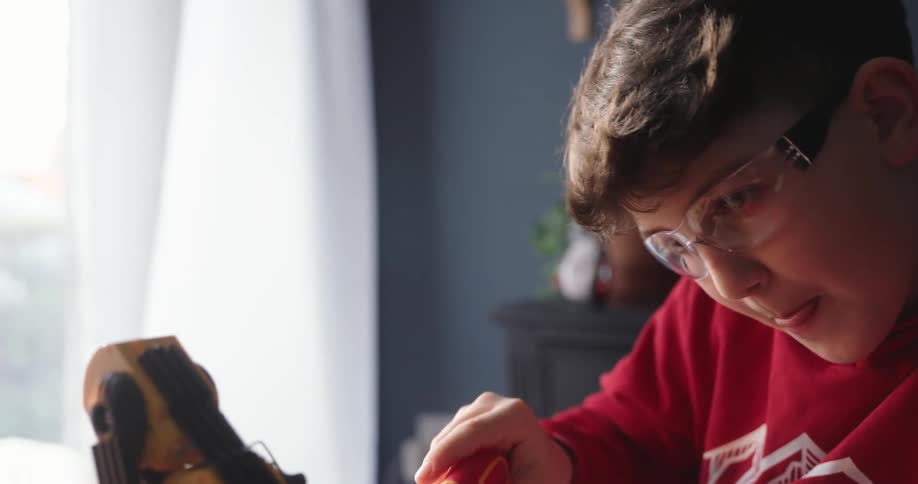 Boy sitting at a desk working on a mechanical arm