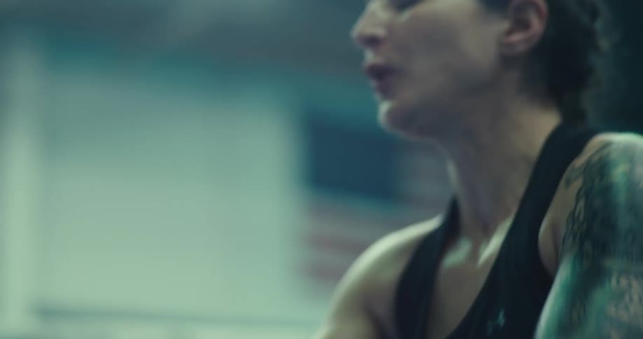 The woman is exercising by lifting large ropes up and down as fast as she can