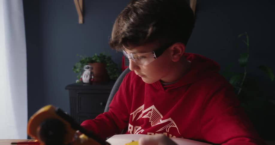 Boy working at a table on a mechanical arm