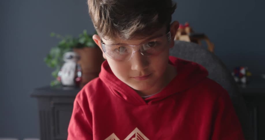 Little boy looking closely at a little robot he has on top of the table