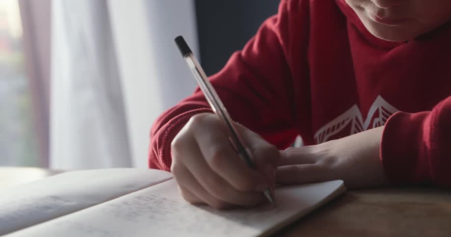 A footage of a boy writing on a book