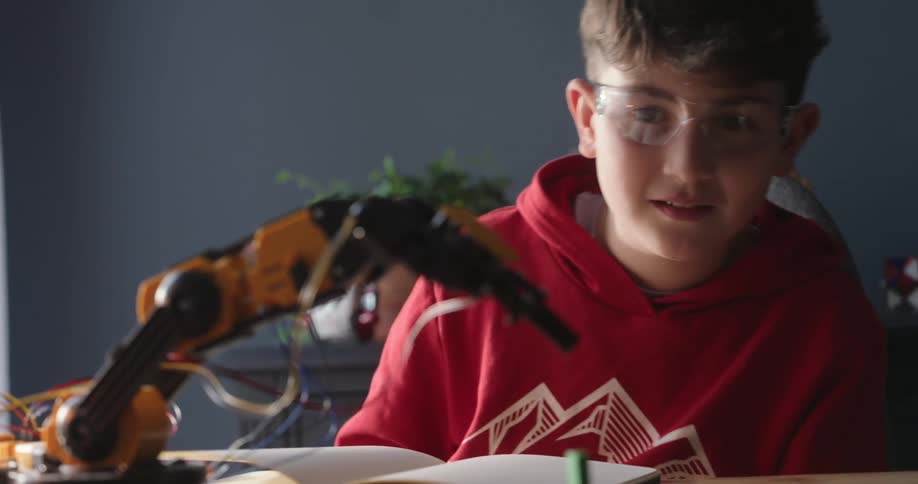 A child watches his robotic arm move up and down