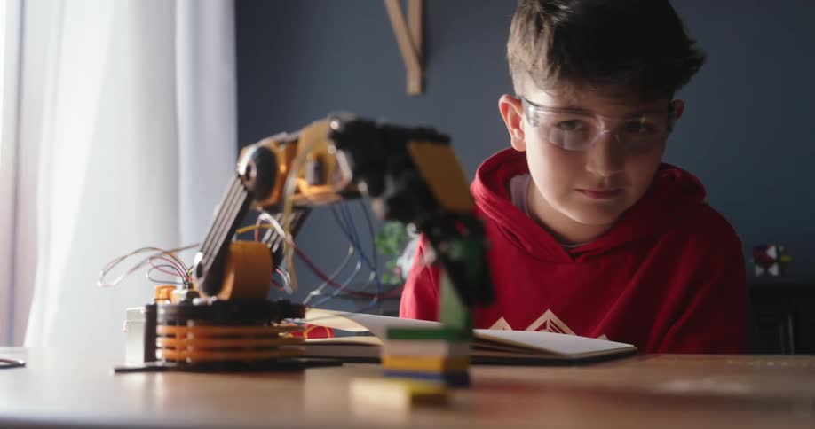 A footage of a boy testing a robotic arm