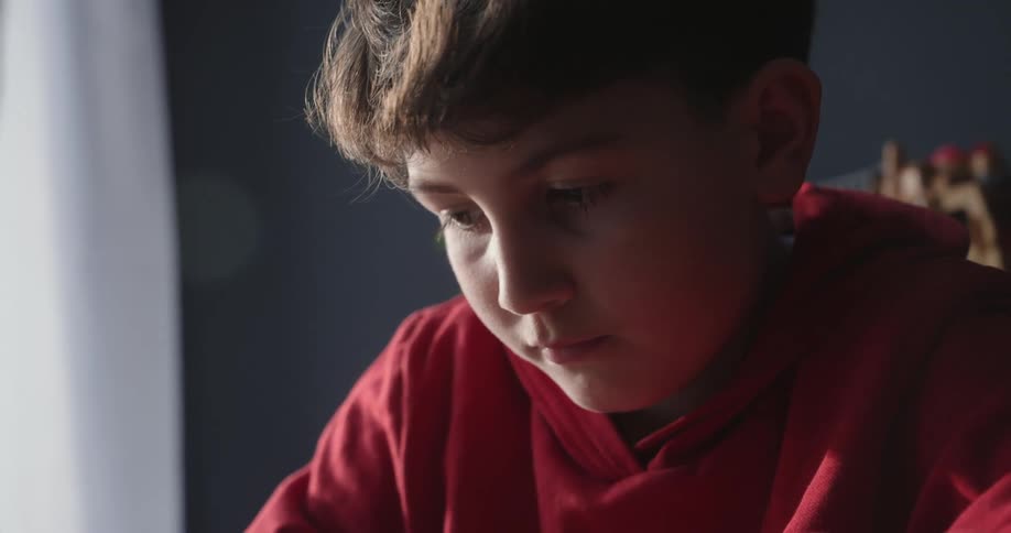 Young sitting at his desk in his room writing in a journal