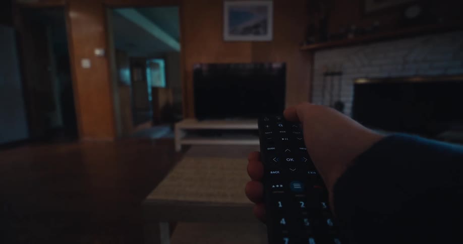 Point of view picking up remote and turning on television