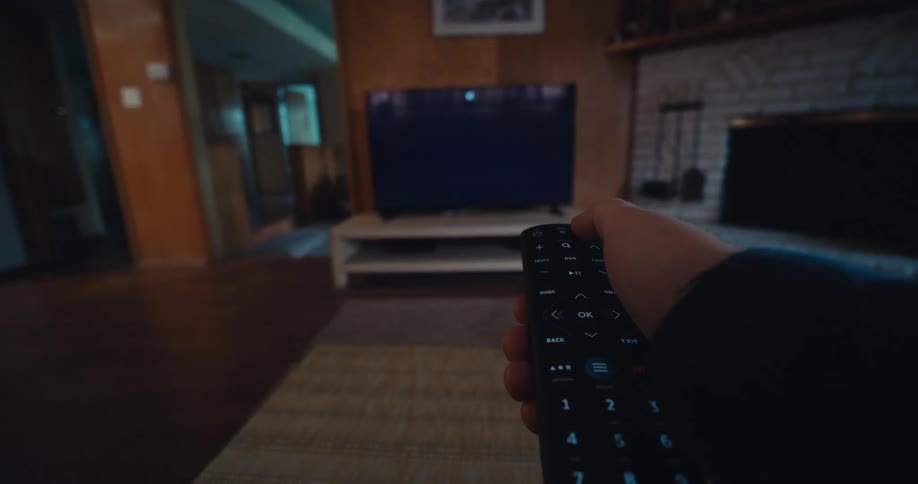 Hand picking up a remote control and turning off the television