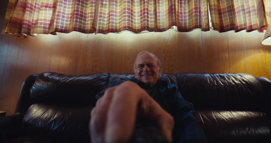 A man is using a remote control and laughing at television