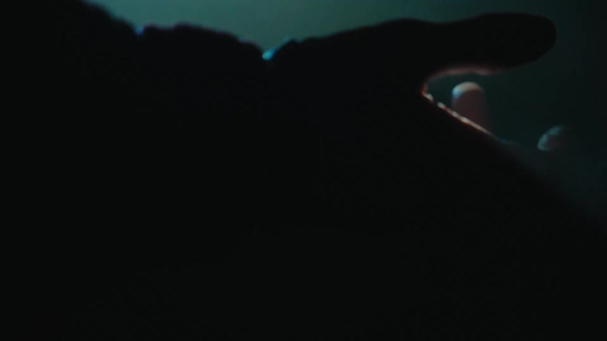 A person reaches their hand in front of the spotlight