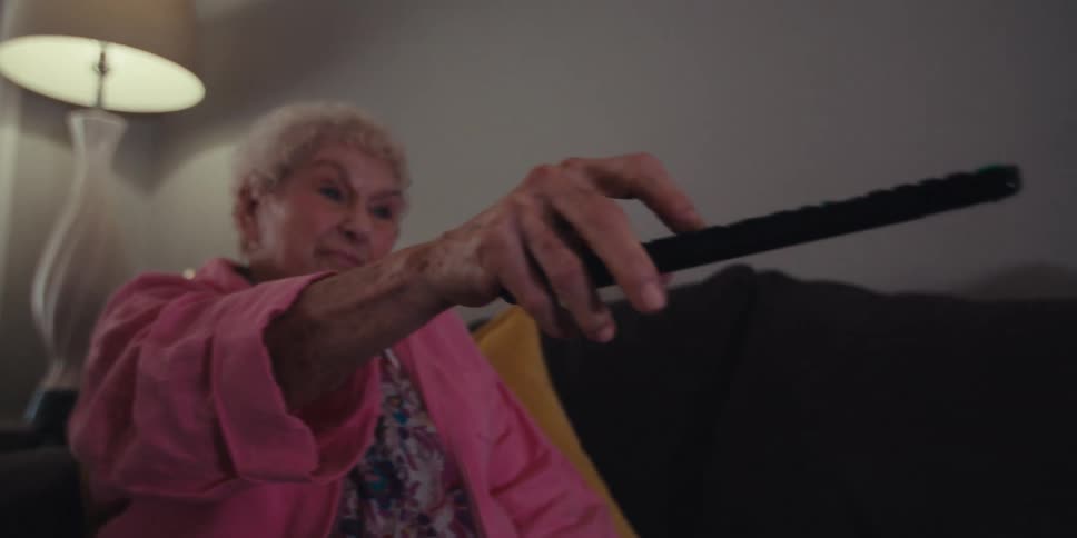 The woman points the remote at the television and presses a button