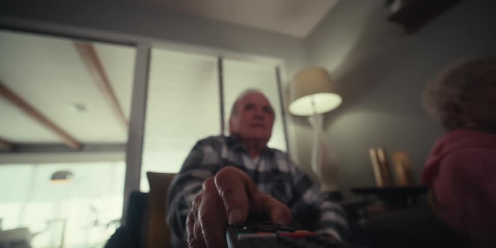 Elderly couple sitting and picking up the television remote control