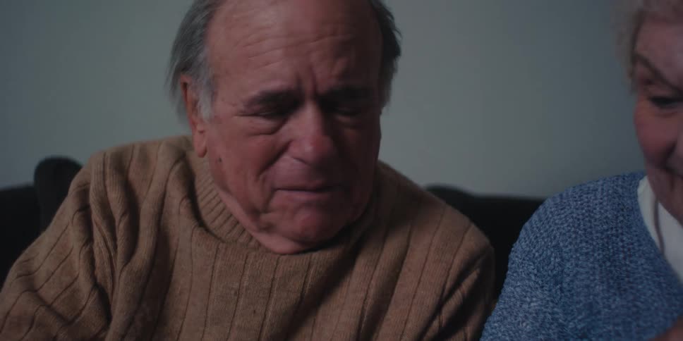 The face of an elderly man and woman who are sitting and talking while looking at a tablet screen