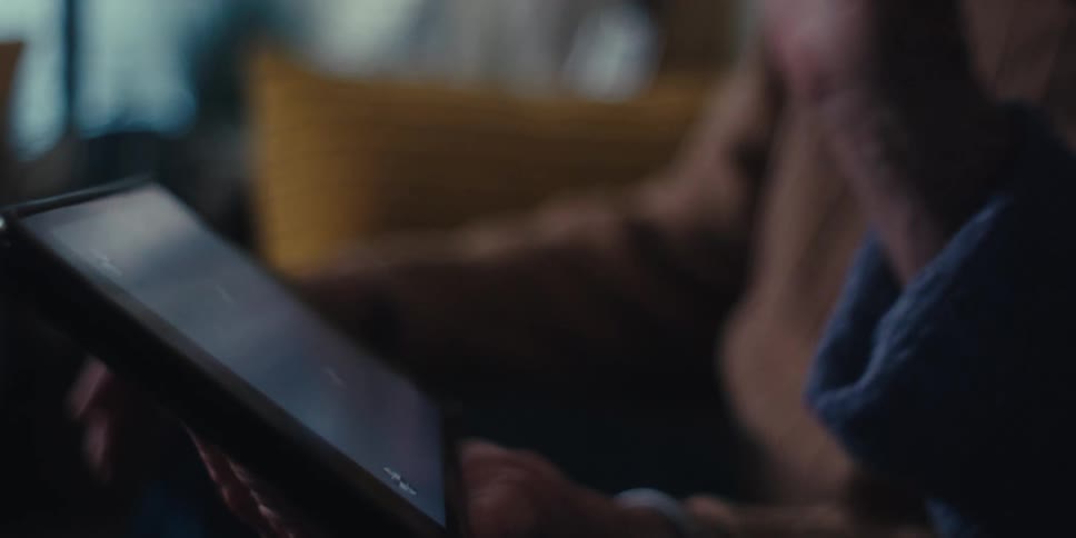 A persons hand touching the screen of a tablet that is being held by their other hand