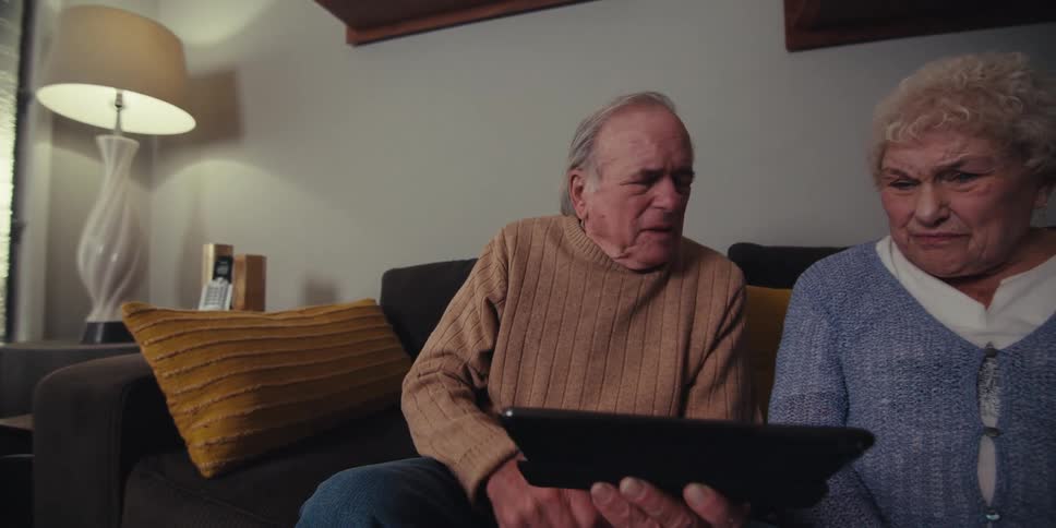 A man slides his finger across the tablet while talking with a woman