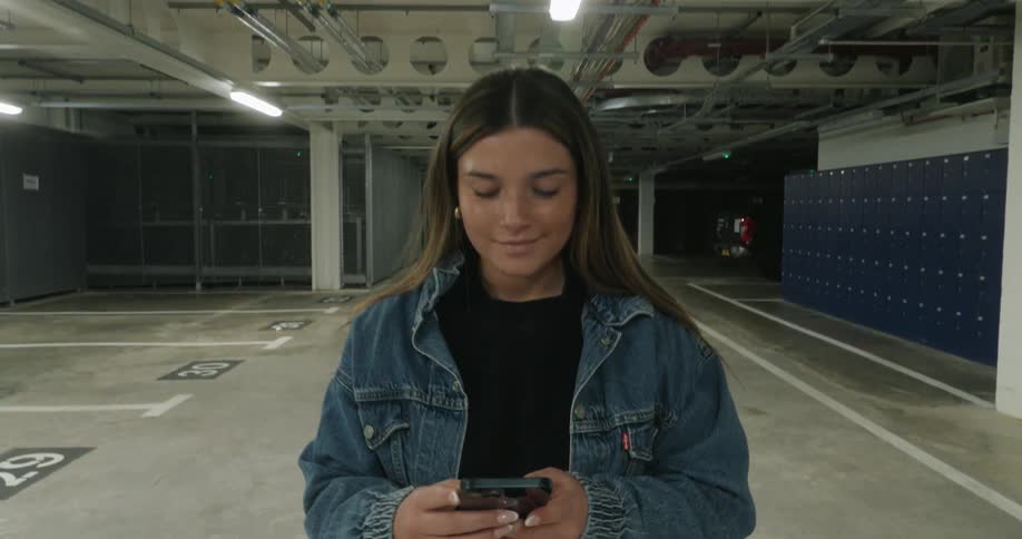 A teenager is using her cell phone by the parking spot