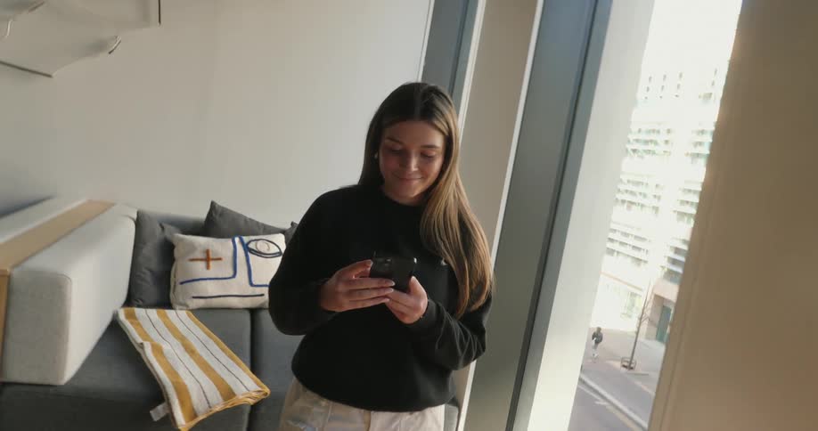 A woman in a living room typing on a cellphone
