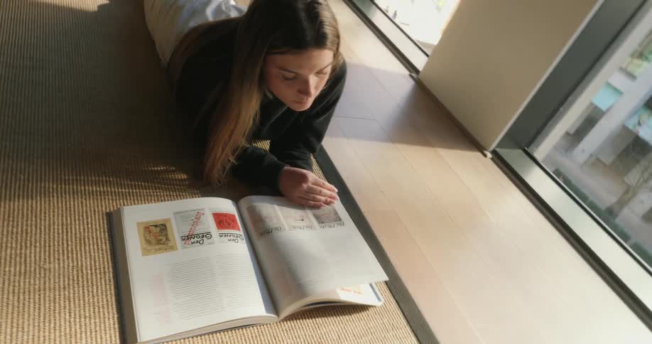 A girl is reading a large book on the floor