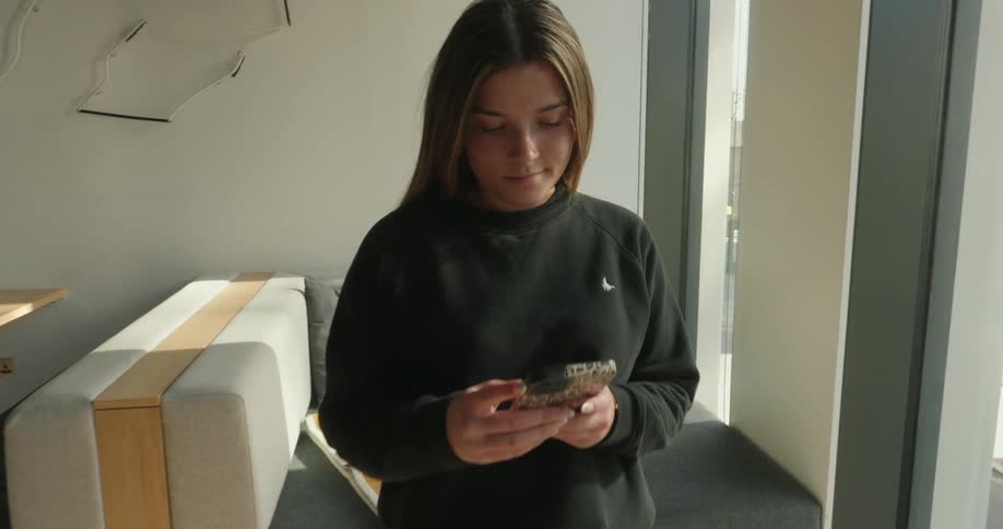 A teenager is using her cell phone indoors