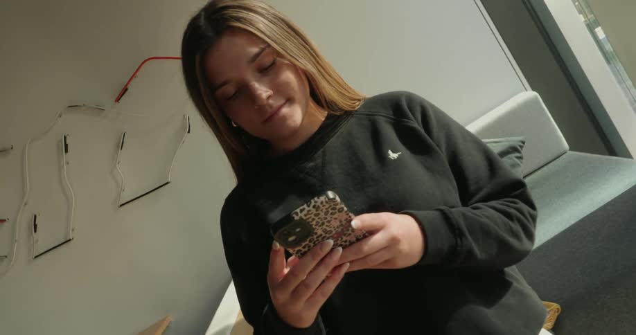 The girl is smiling as she texts on her phone