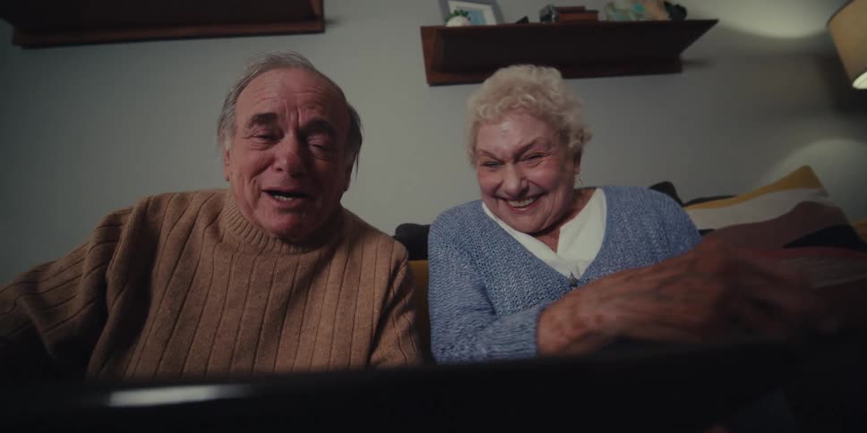 A man and woman laugh and talk on a video call