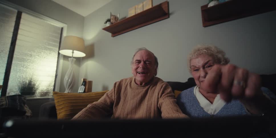 Elderly couple sitting side by side with a happy facial expression