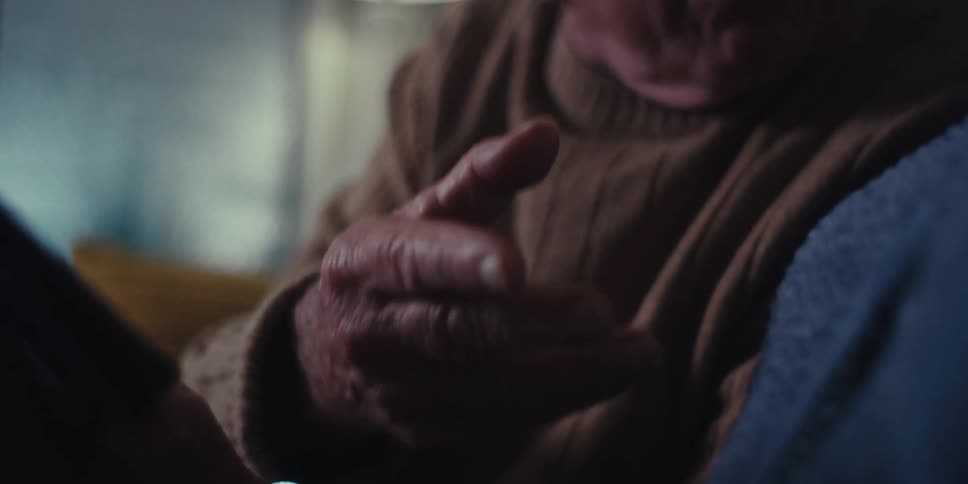 A man talks with someone while waving and pointing at a tablet