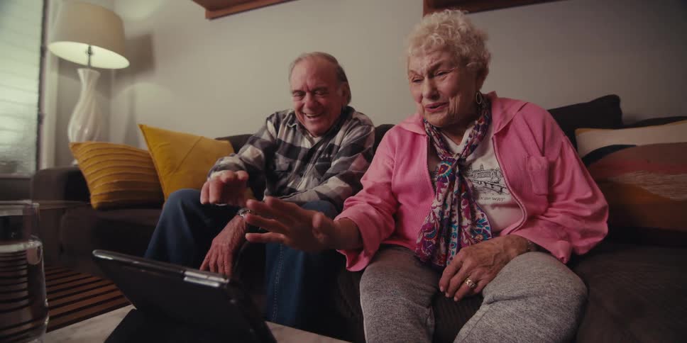A man and woman wave and talk to the tablet