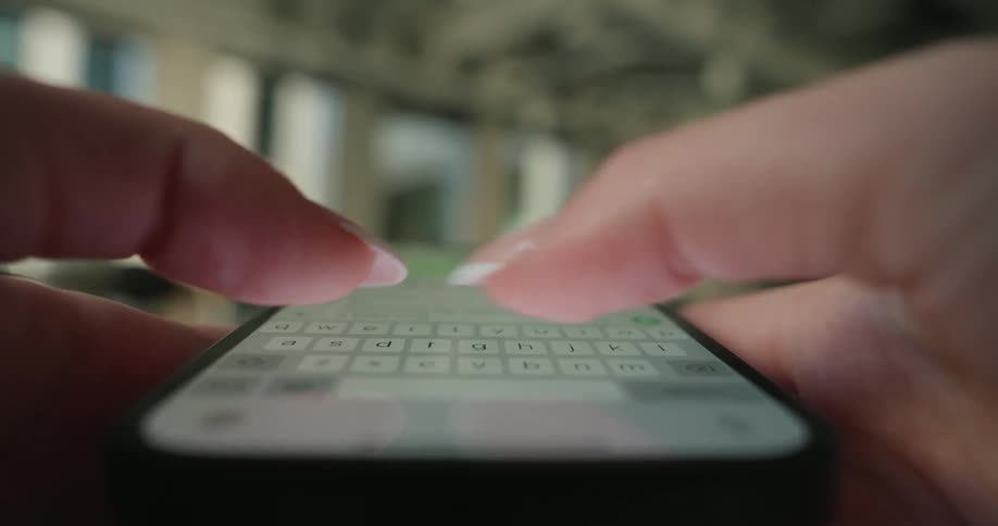 Womans fingers typing on a smartphone screen with a blurred background