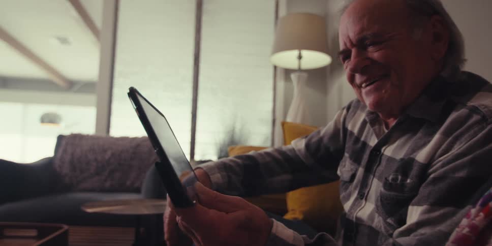 Grandma and grandpa are smiling while talking to their grandchildren on a tablet