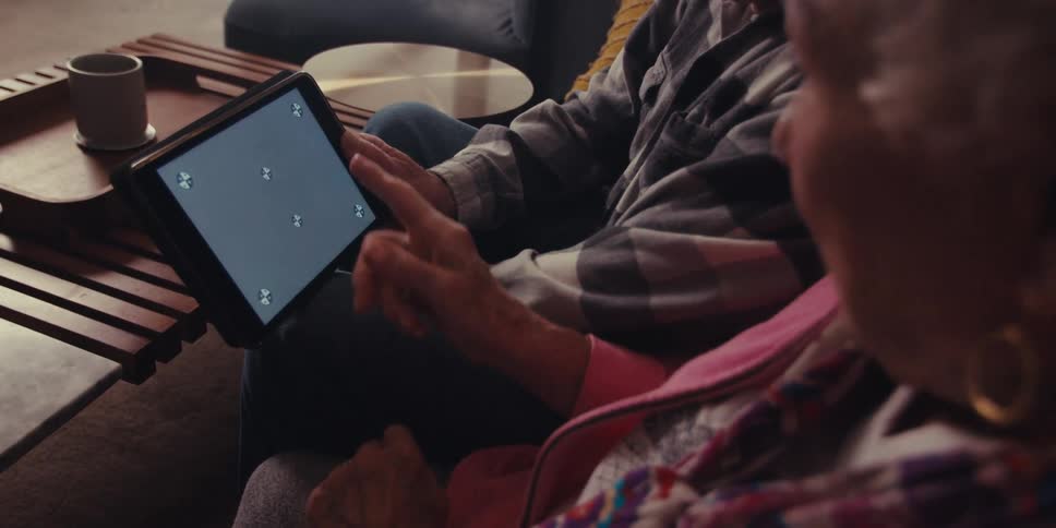 A woman talks with a man and points at the tablet