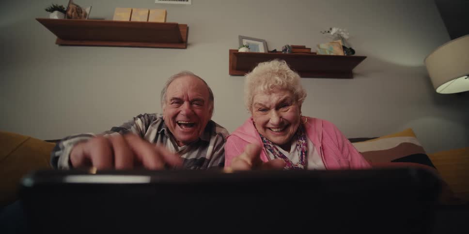A man and woman wave and talk on a video call