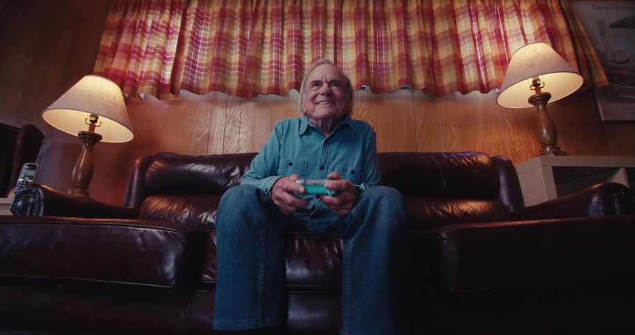 A man is enjoying himself playing video games on his couch