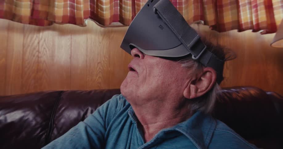 A man looks around and swings a virtual reality controller