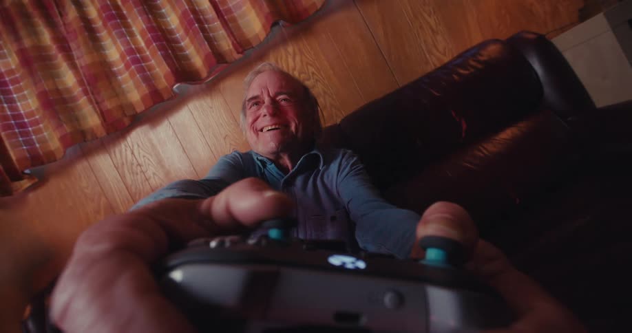 Elderly man holding a wireless video game controller and playing having fun