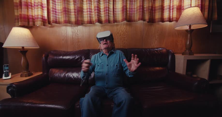 Elderly man laughing having a great time wearing virtual reality goggles
