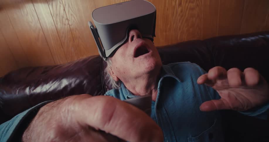 A man moves the controller around while using a virtual reality headset