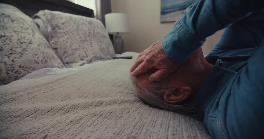 A man is laying in bed with his hands on his face