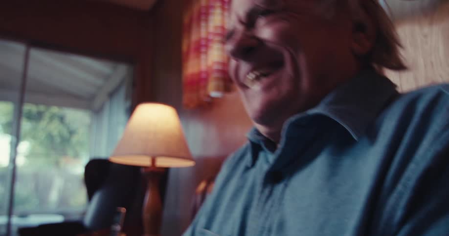 A man laughs as he watches television