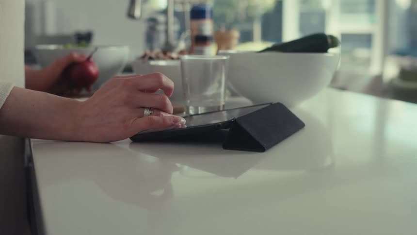 A woman scrolls through a recipe as she cooks