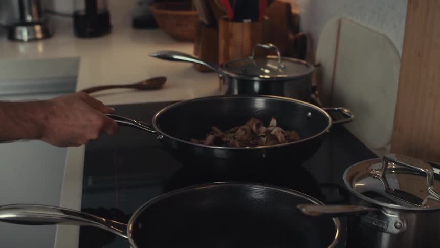 Sauteing mushrooms in a saute pan over a black cook top