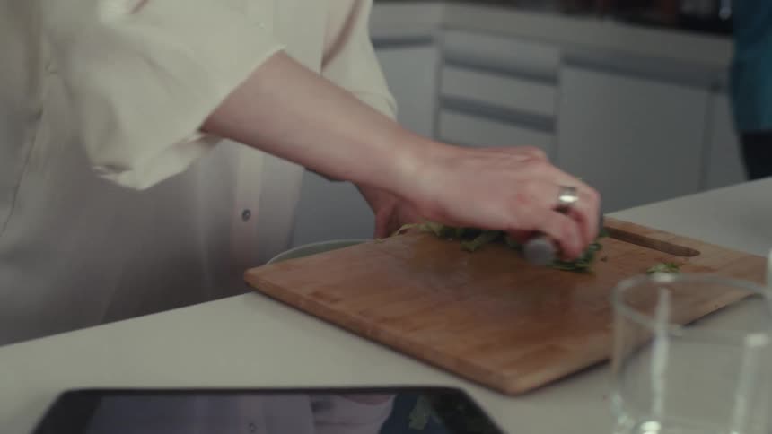 A woman puts cut vegetables in a bowl