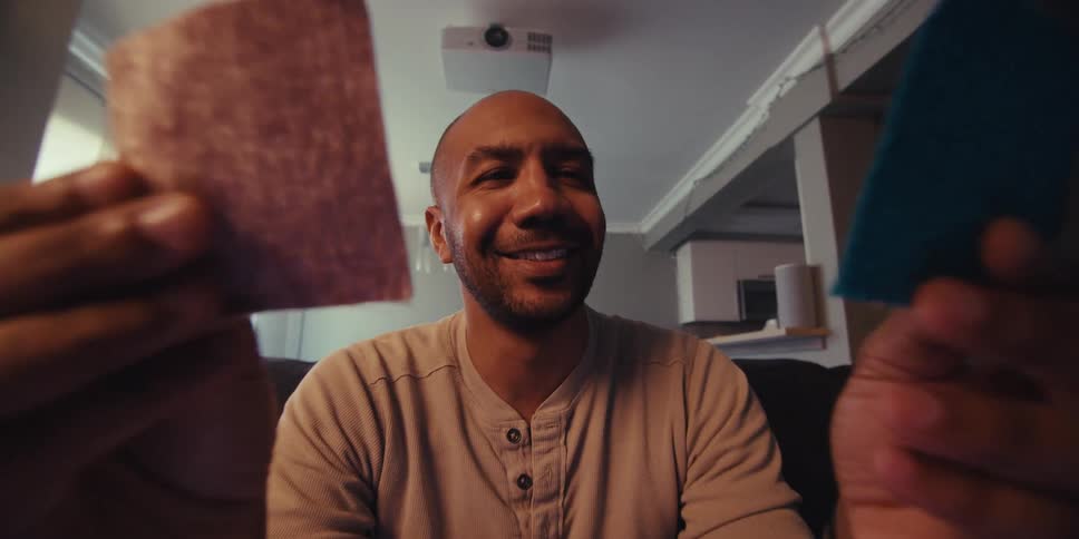 A footage of a man holding and smiling at the cards he is holding
