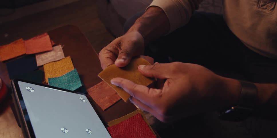 Man sitting near a tablet compares small swatches of fabric