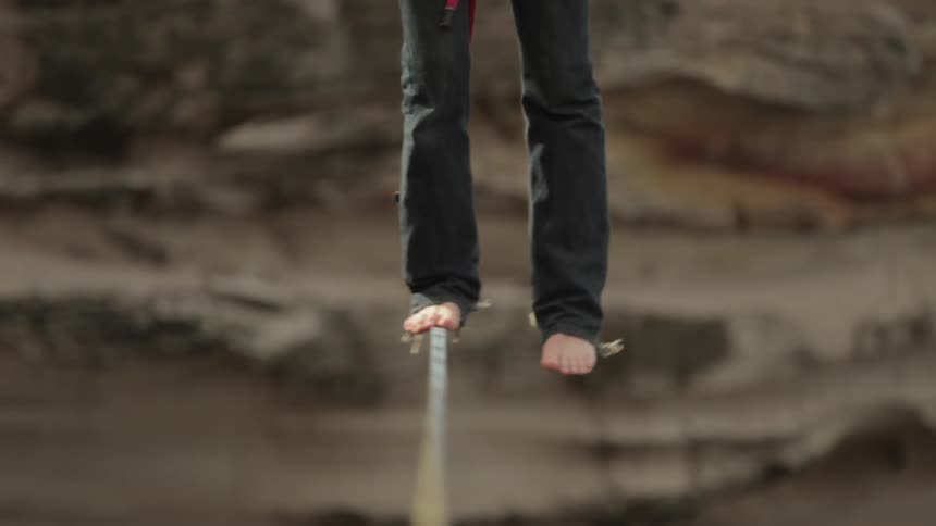 Man balancing on a tightrope in a canyon
